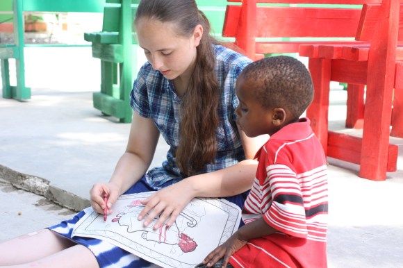 Abby Fleischer of Cross Church in Carlingille colors with a young boy at New Life.